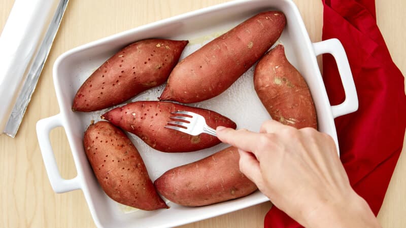 Sweet potatos are being pined with fork.